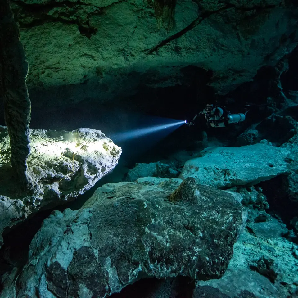 Diver crossing the clear cavern of Cenote Dos Ojos