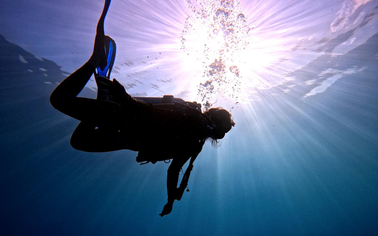 Diver silhouetted against the sun below the surface in Cancun