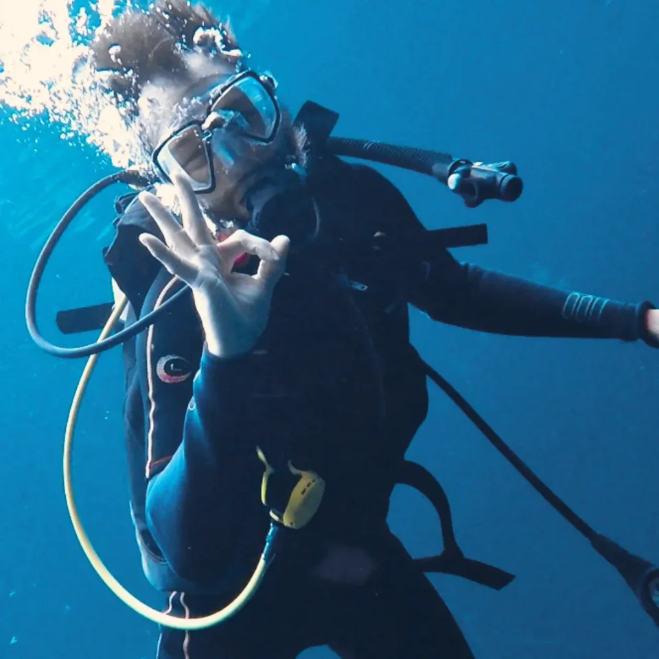 Diver giving the OK sign in the blue water of Cenote Car Wash