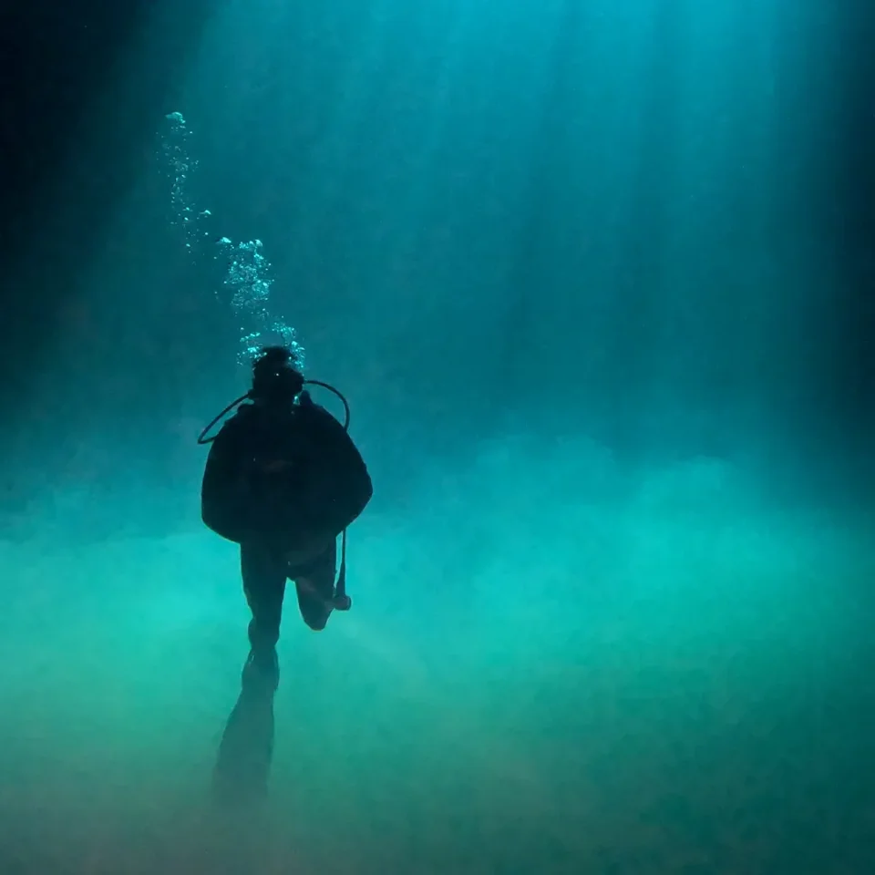 Diver silhouetted inside the beam of light at Cenote Maravilla